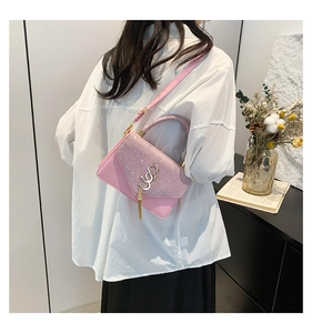 Rear view of a pink crossbody bag with sequin flap and gold tassel on a white shirt