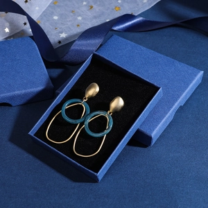 Blue jewelry gift box with gold and teal geometric earrings on black velvet lining