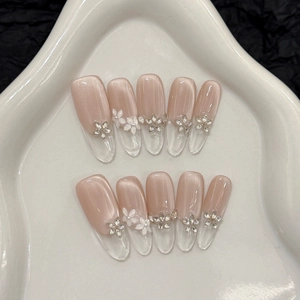 Cat eye press-on nails with 3D white flowers and rhinestones on a heart tray