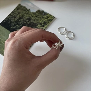 Detail showing 925 sterling silver bow and knot rings on hand with a nature background
