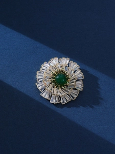 Detailed macro view of a floral brooch with green center stone and sparkling zircons