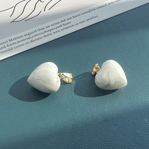 Detail of heart-shaped white stone pendants with gold clasps on blue textured leather