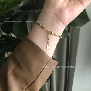 Detailed view of an 18K gold-plated titanium cuban chain bracelet on a woman's wrist