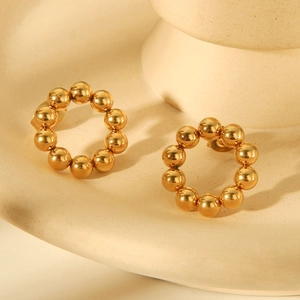 Detailed view of gold ball bead hoop earrings on white ceramic for luxury aesthetic