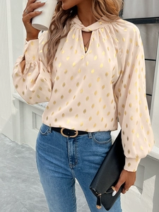 Detail of pink long-sleeve blouse with gold polka dots and stylish stand collar v-neck