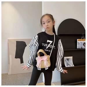 Detail of straw handbag with pink bow and pearls paired with a kid's black sweatshirt