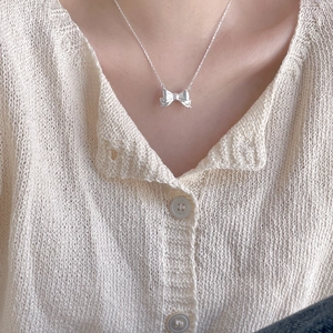Minimalist 925 silver bow pendant necklace worn by a model in soft lighting