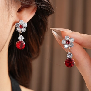 Close-up of zircon flower earrings with red and white gemstones in silver finish