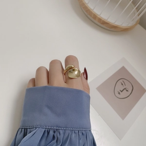Detail of minimalist gold droplet open ring on index finger with artistic lifestyle decor