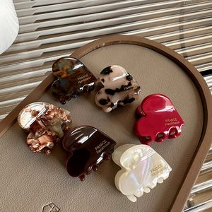 Set of 6 heart-shaped acetate hair claws in various colors on a leather tray