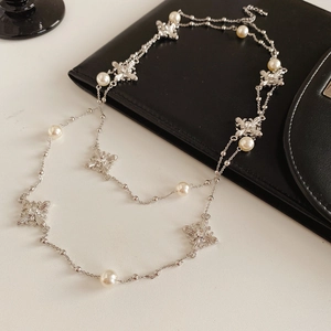 Détails de nœuds argentés avec pierres claires et perles blanches sur un collier raffiné
