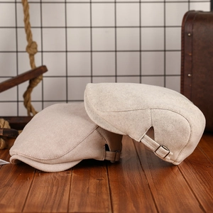 Warm wool blend newsboy flat cap in beige with adjustable side buckle on wood table