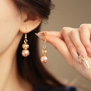 Detailed shot of hollow gold beaded earrings with large rose gold pearl accents