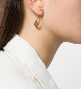 Close-up of a gold safety pin earring made of polished titanium steel on model