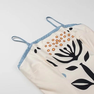 Detail of floral print dress with thin blue straps and mesh paneling on beige fabric