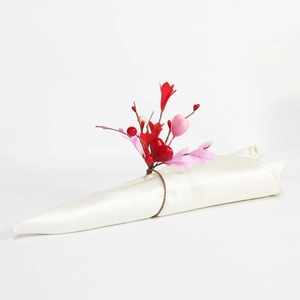 Macro view of heart-shaped napkin ring with red berries on white satin cloth