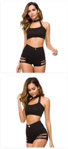 Dettaglio degli shorts neri a vita alta con fibbie metalliche e crop top allacciato al collo