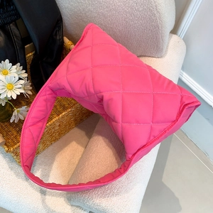 Quilted nylon shoulder bag in hot pink with diamond stitching on a white boucle chair