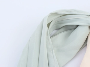 Detail shot of light green pleated fabric with precise double stitching craftsmanship