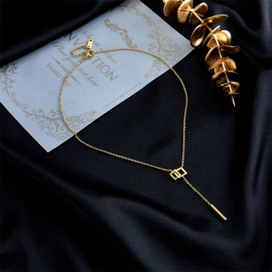 Chic gold-tone titanium steel necklace with square rings and long bar pendant on black satin