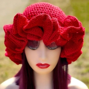 Close-up of a handmade red crochet knit hat with large artistic ruffled flower detail