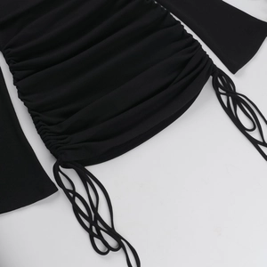 Dettaglio dell'abito in maglia a coste nere con coulisse laterale e texture a pieghe eleganti