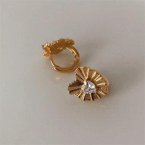 Macro detail of heart-shaped gold hoop earrings with zircon stone and pleated texture