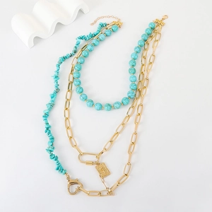 Detail of layered turquoise necklace with irregular stones and golden heart clasp