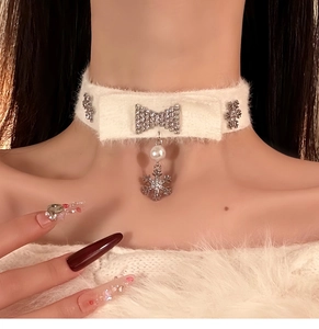 Detail view of white knitted bow choker featuring snowflake and pearl charms on neck