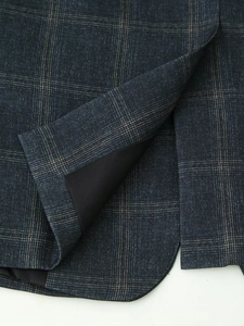 Macro view of blue plaid blazer showing detailed stitching on the hem and side slit
