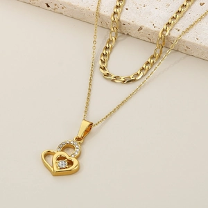 Close-up of golden double-layered necklace with interlocking heart pendant and rhinestones