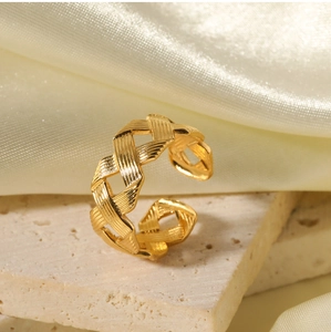 Detailed shot of golden braided stainless steel open ring on a textured stone base