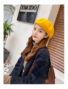 Detail of warm yellow wool beret hat with classic crown on model in outdoor cafe setting