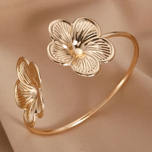 Polished gold flower cuff bracelet with textured petals on beige silk fabric