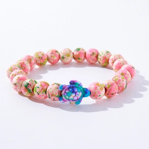 Close-up of pink spotted stone beads with a blue and purple turtle charm bracelet