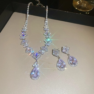 Detailed close-up of water drop zircon necklace and earrings set on beige jewelry tray