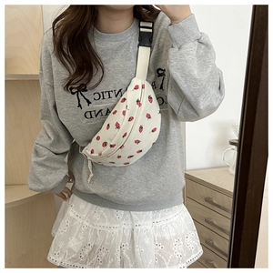 Close-up of cream corduroy crossbody bag with red strawberry pattern and adjustable strap