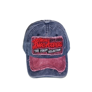 Close-up of vintage blue denim baseball cap with distressed embroidery and red patch detail