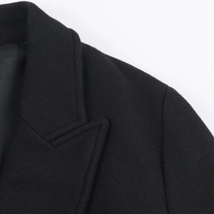 Close-up of premium black wool blend coat showing high-quality twill fabric texture