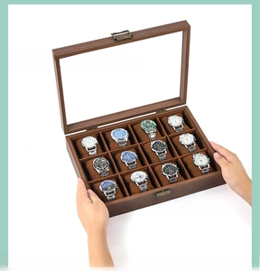 Close-up of a 12-slot walnut wood watch storage box with glass top and metal clasp