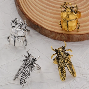 Dettaglio di anelli a insetto vintage con trame di scarabeo e cicala su legno