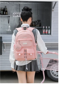 Pink multi-pocket waterproof nylon backpack with a round smiley coin purse charm