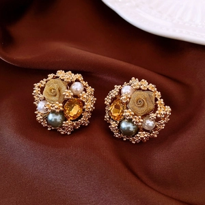 Macro shot of vintage gold flower earrings with pearls and amber gemstones