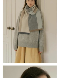 Detail view of a knitted color-block scarf featuring beige, grey, and light blue tones