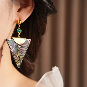 Close-up of vintage triangle earrings with green gemstones and colorful resin on a model