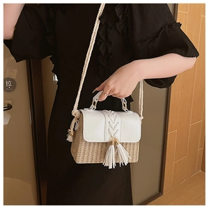 Close-up of woven straw and white leather crossbody bag with tassel and rope strap