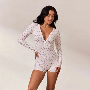 Gros plan sur un combishort blanc à manches longues avec fleurs rouges et boutons avant