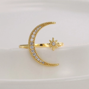 Star and moon gold-plated open ring with shimmering pavé zircon stones on white background
