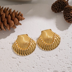 Detailed view of 18K gold plated shell earrings with diamonds on textured stone pedestal