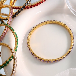 Tennis bracelet with multi-color zircons on 18K gold plated base in a white ceramic dish